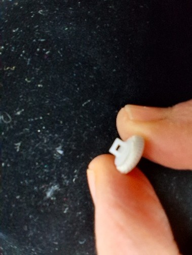 Close-up of the reverse of a satin covered bridal button showing a broken shank that has split away from the button back
